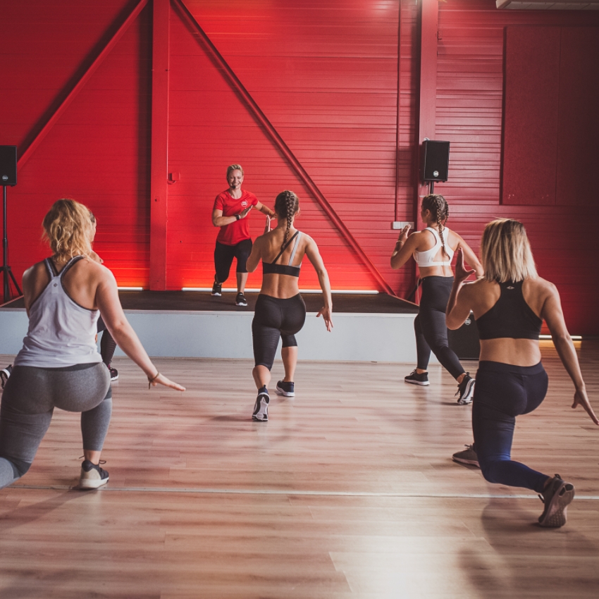 Des sportifs réalisent des exercices sportifs d'après l'exemple d'une coach