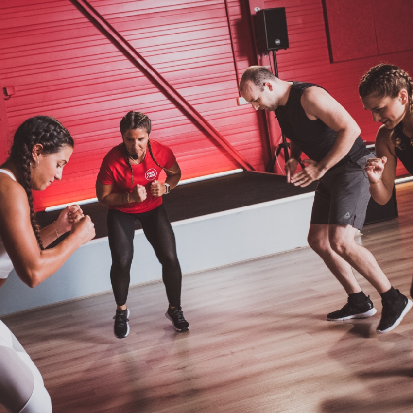 Un coach Neoness motive des sportifs pendant un cours de Body Attack